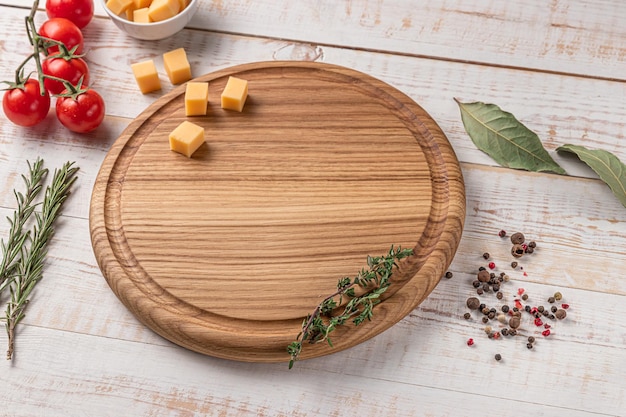 Ronde houten snijplank met rand cherrytomaatjes plakjes kaas en kruiden op een witte achtergrond mockup met kopie ruimte voor tekst zijaanzicht