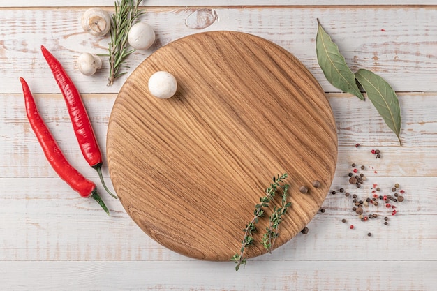 Ronde houten snijplank van donkere kleur met lege ruimte champignons, chili peper en specerijen op een witte achtergrond mockup met kopieerruimte voor tekst bovenaanzicht