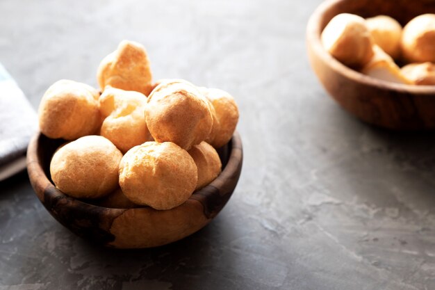 Ronde kleine verse zelfgemaakte eclairs in een houten ronde beker op een donkere achtergrond.