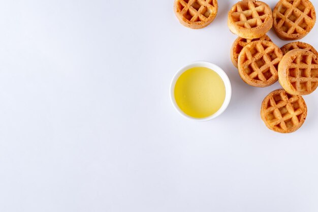 Ronde kleine wafels en een kopje met honing op een witte achtergrond