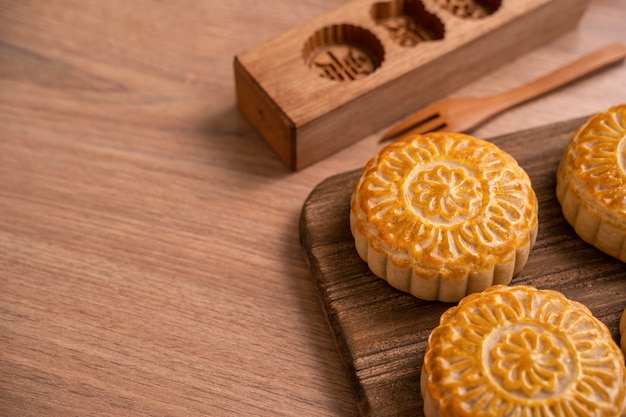 Ronde maancake Mooncake - traditioneel gebak in Chinese stijl tijdens Mid-Autumn Festival / Moon Festival op houten achtergrond en dienblad, close-up