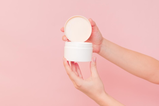 Ronde pot cosmetische crème in de hand op roze achtergrond Cosmetische schoonheidsmodel voor productbranding