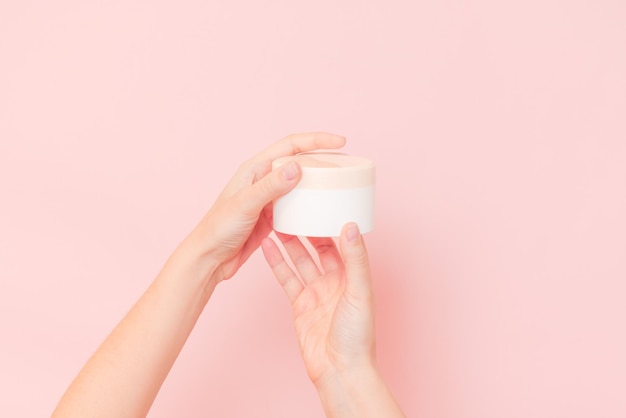 Ronde pot cosmetische crème in de hand op roze achtergrond Cosmetische schoonheidsmodel voor productbranding