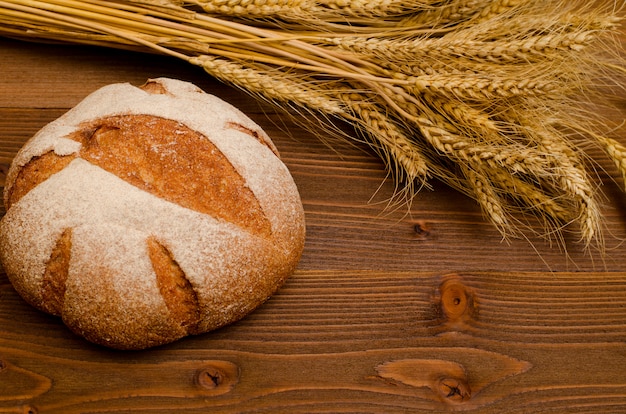 Ronde roggebrood en oren van tarwe op een houten tafel, bovenaanzicht