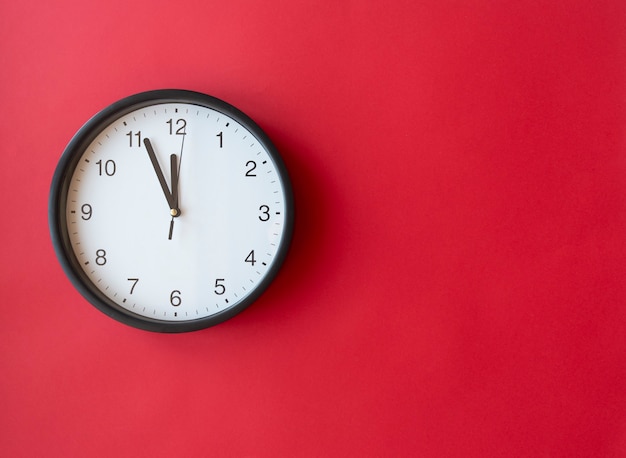 Ronde wandklok op rood oppervlak met 12