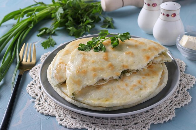 Foto ronde zelfgemaakte khachapuri cakes met brynza kaas gebakken in een pan blauwe achtergrond closeup