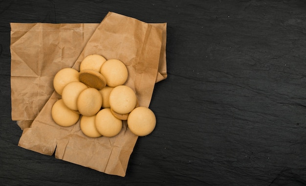 Ronde zelfgemaakte koekjes bovenaanzicht op donkere achtergrond. Gemorste koekjes met inpakpapier