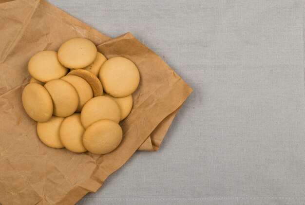 Ronde zelfgemaakte koekjes bovenaanzicht op donkere achtergrond. Gemorste koekjes met inpakpapier