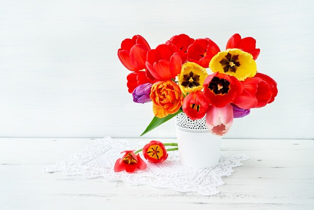 Rood ans geel tulpenboeket in witte vaas op wit. vakantie, kopieer ruimte.