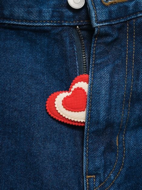Rood en wit hart dat uit de open gulp blauwe spijkerbroek steekt.