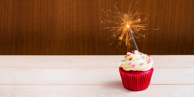 Rood fluweel cupcake met sterretjeverlichting over houten achtergrond