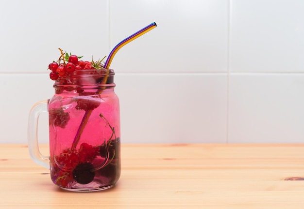Rood fruitwater in glazen pot met herbruikbaar metalen rietje Ruimte kopiëren