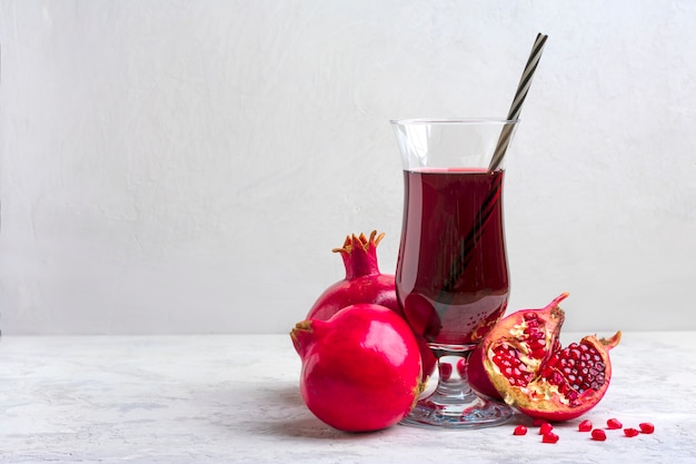 Rood granaatappelsap in een glas op grijze achtergrond