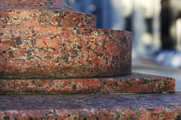 Rood granietpostament in de stad als steenachtergrond