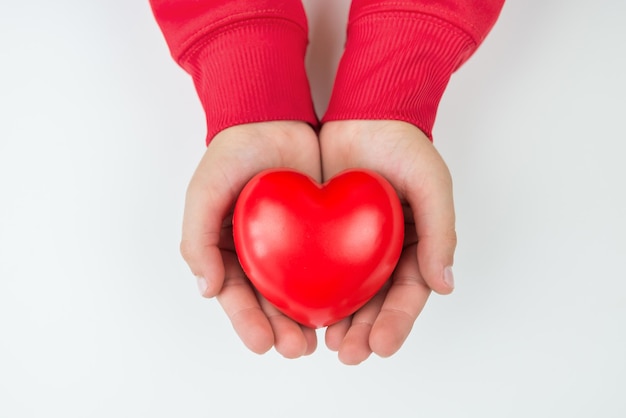 Rood hart in de handen van kinderen geïsoleerd op wit uitzicht van bovenaf handen houden een hart vast