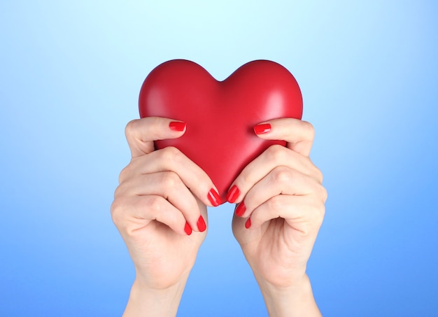 Rood hart in handen van de vrouw op blauwe achtergrond