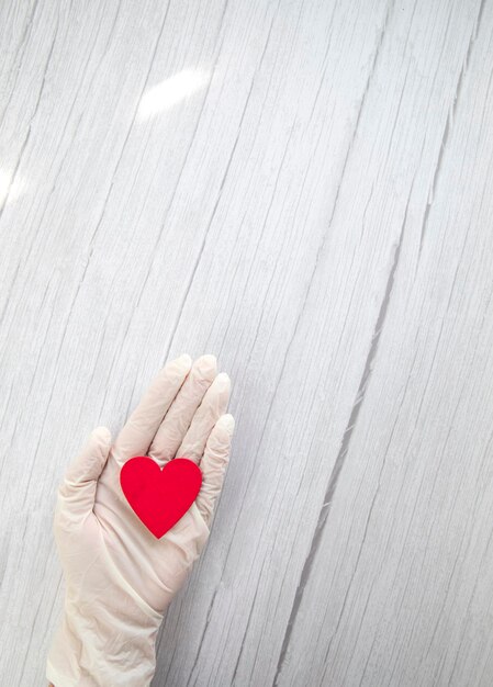 Rood hart in witte beschermende medische handschoenen bovenaanzicht achtergrond voor de dag van de medic covid coro...