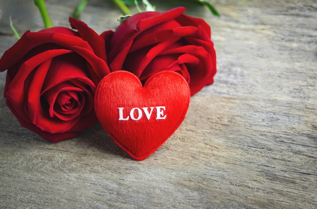 Rood hart met liefdetekst en rood roze bloemen op houten oppervlakte