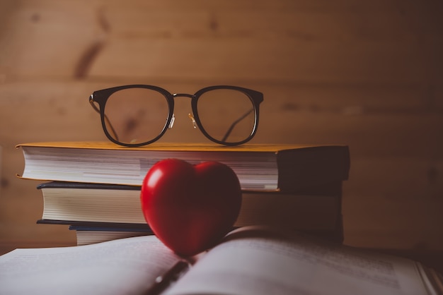 Foto rood hart met open boek en pen op houten tafel