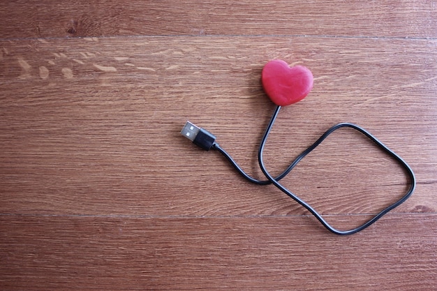 Rood hart met usb-kabel op houten achtergrond liefde en technologie concept