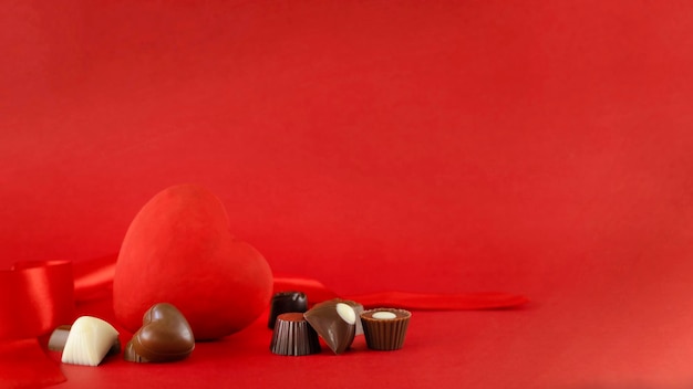 Rood hartcijfer en chocoladetruffels tegen rode achtergrond Saint Valentine dag concept