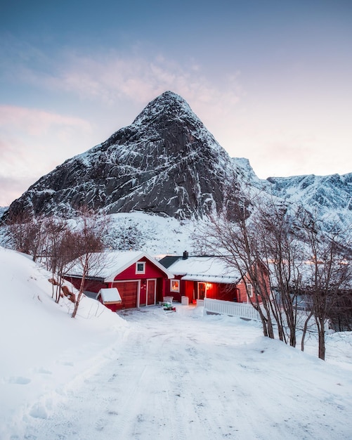 Rood huis met droge boom in de bergen in de winter 's avonds