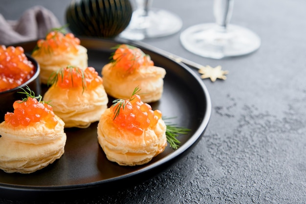 Rood kaviaar toast van zalm kerstcanape of toast met rood kaviar op een zwart bord op een donkere achtergrond idee voor een kerstsnack Gourmet eten Textuur van kaviaar zeevruchten