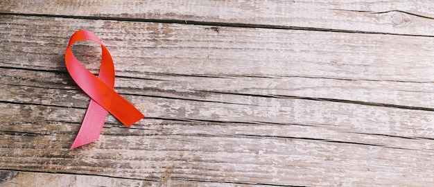 Rood lint als symbool van aids-bewustzijn op houten tafel, bannerformaat, copyspace voor uw individuele tekst.