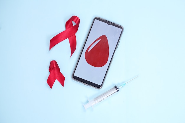 Rood lint en bloed op het symbool van het smartphonescherm tegen hiv geïsoleerd op blauwe achtergrond