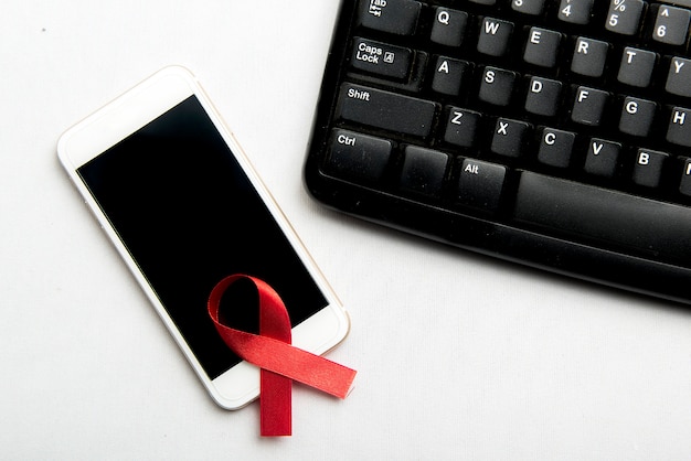 Rood lint en mobiele telefoon met witte achtergrond. Hiv Aids lint bewustzijn