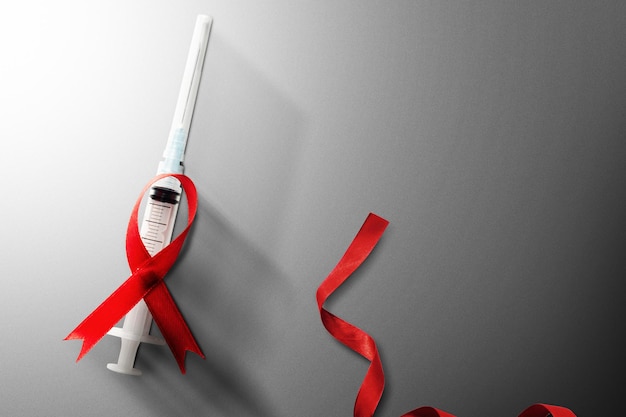 Rood lint en spuit met witte achtergrond. Hiv Aids lint bewustzijn