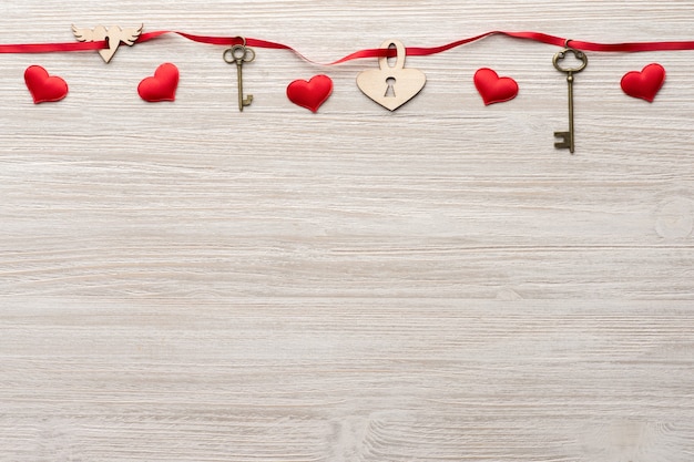 Rood lint gaat door twee vintage sleutels en een hartslot op houten achtergrond voor Valentijnsdag