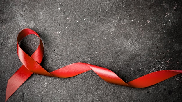 rood lint op een donkergrijze achtergrond. symbool van de Wereld Aidsdag of kanker of HIV Awareness Month en concept van de gezondheidszorg. Kopieer ruimte