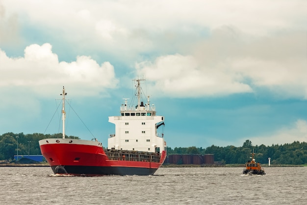 Rood nieuw vrachtschip dat naar het buitenland verhuist. Productexport in Europa