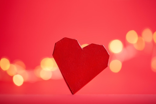 Rood papier handgemaakt hart op rode achtergrond met feestelijke boke Creatieve wenskaart voor Sint Valentijn