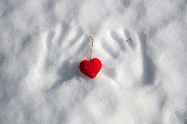 Rood pluche hart en handafdrukken in de sneeuw