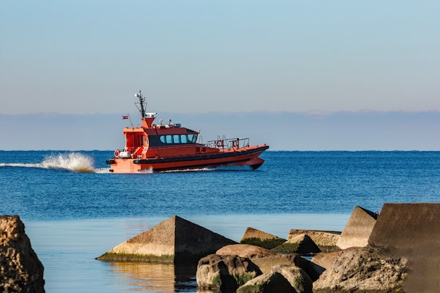 Rood proefschip beweegt met snelheid voorbij de golfbreker