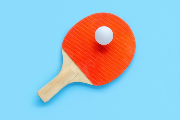 Rood racket voor tafeltennis met witte bal op blauwe achtergrond pingpong sportapparatuur