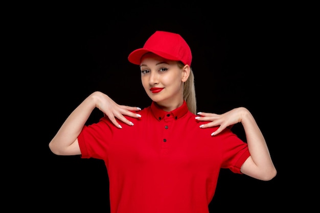 Rood shirt dag lachend meisje dat de schouders aanraakt in een rode dop met shirt en felle lippenstift