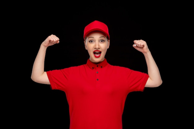 Foto rood shirt dag super blij schattig meisje met vuisten in een rode dop met shirt met lippenstift