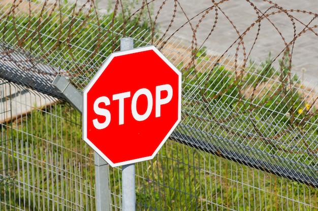 Rood stopbord in de buurt van het hek met prikkeldraad.