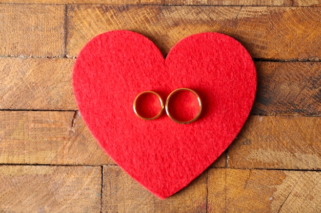 Rood vilt hart en trouwringen op houten close-up als achtergrond