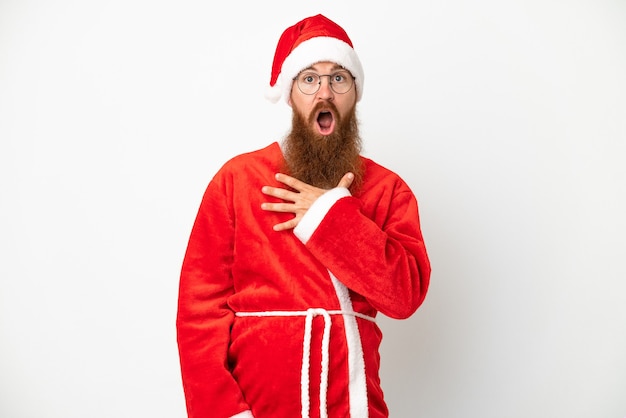 Roodachtige man vermomd als de kerstman geïsoleerd op wit verrast en geschokt terwijl hij naar rechts kijkt