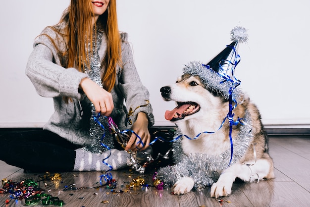 Roodharig gelukkig meisje zittend op de vloer met haar grote hond die het nieuwe jaar en kerst viert