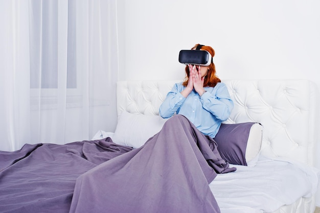 Roodharig meisje in bed met vr-bril op studiokamer