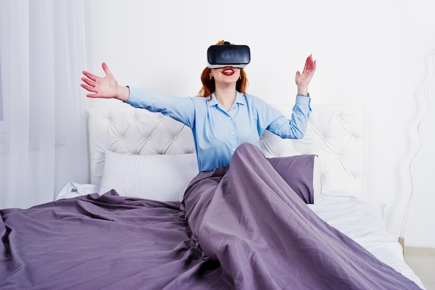 Roodharig meisje in bed met vr-bril op studiokamer