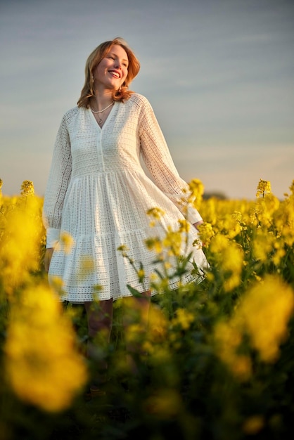 Foto roodharig meisje in witte jurk in raps veld