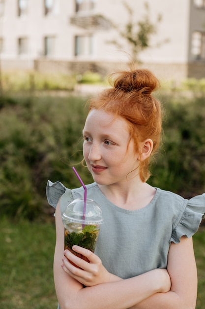 Roodharig meisje met een glas limonade in haar handen.