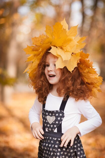 Roodharig meisje met een krans van herfstbladeren op haar hoofd