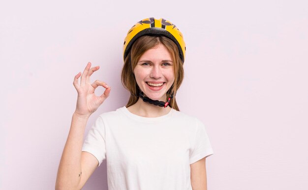 Roodharig mooi meisje voelt zich gelukkig met goedkeuring met een goed gebaar fietsconcept
